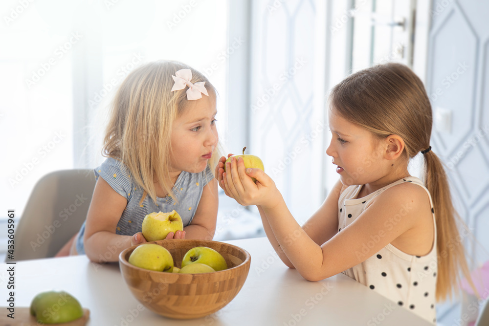 Children in the kitchen have fun and eat apples, kids cook breakfast together, cut an apple with a knife in a bright interior Children in the kitchen have fun and eat apples, kids cook breakfast together, cut an apple with a knife in a bright interior