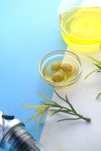 bottle of olive oil and fresh olive in a container on color background .
