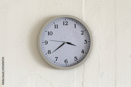 Round clock hanging on the white wall