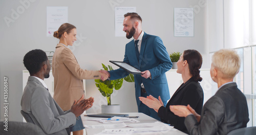 Young male executive congratulating and giving certificate to female employee photo