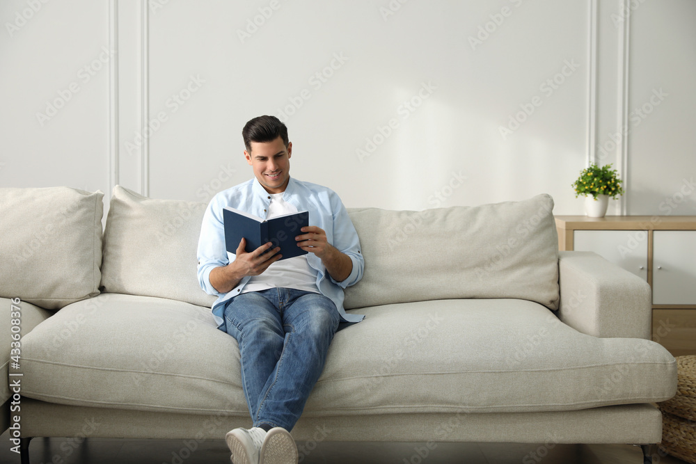 Man with book sitting on comfortable sofa in living room Man with book sitting on comfortable sofa in living room