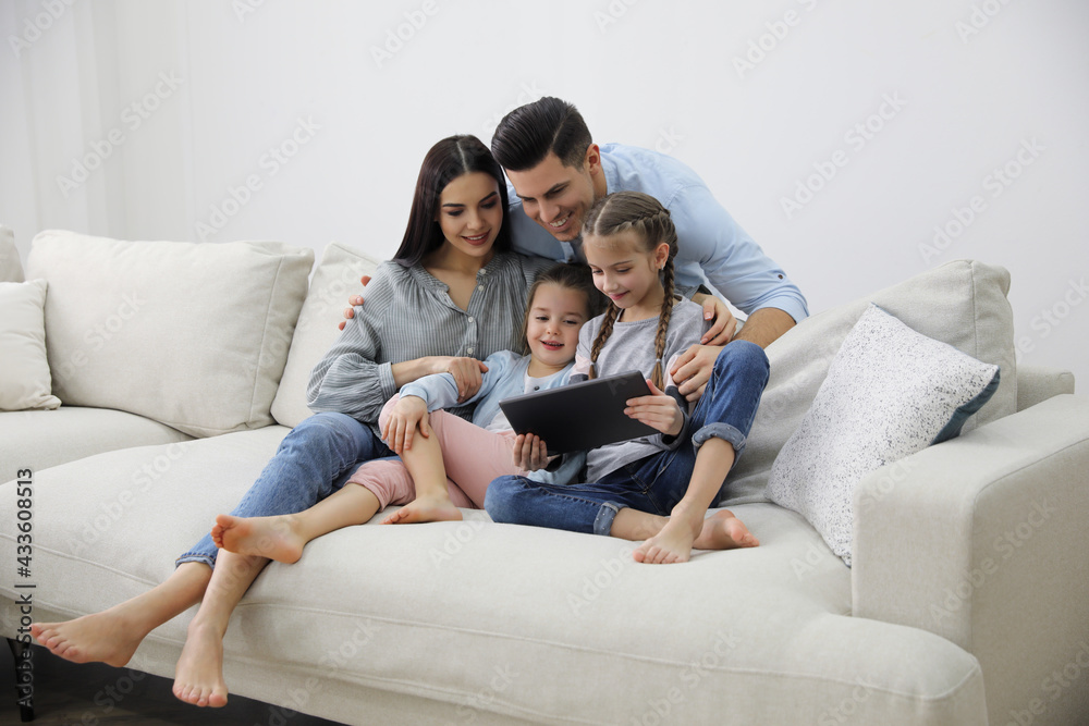 Family with tablet sitting on comfortable sofa in living room Family with tablet sitting on comfortable sofa in living room