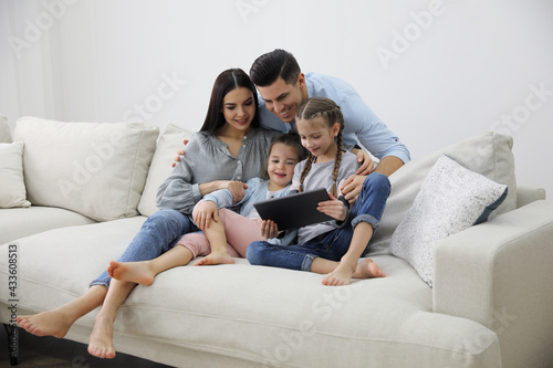 Fotografie Family with tablet sitting on comfortable sofa in living room
