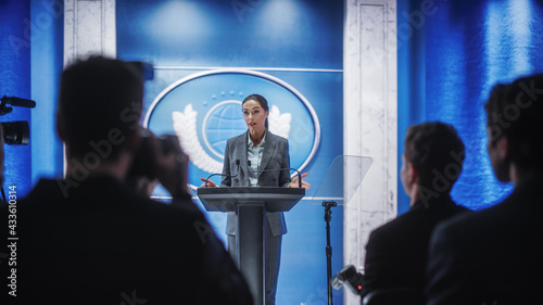 Organization Female Representative Speaking at a Press Conference in Government Building. Press Office Representative Delivering a Speech at a Summit. Minister Speaking to a Congress Hearing.