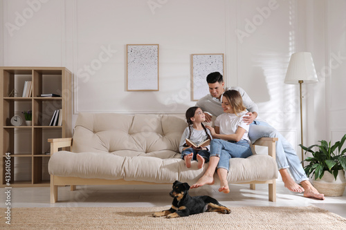Happy family on sofa and puppy in living room