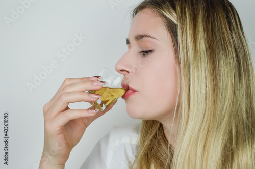 Portrait of a beautiful young blonde woman sipping a shot of liqueur