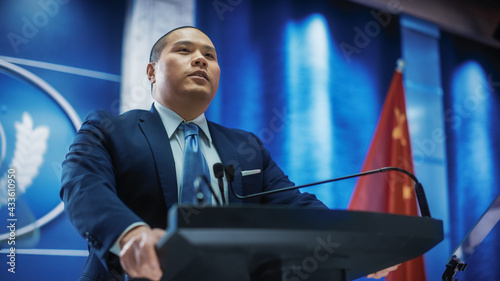 Portrait of Chinese Organization Representative Speaking at Press Conference. Minister Delivering a Speech at Congress. Backdrop with United States of America and People's Republic of China Flags. photo