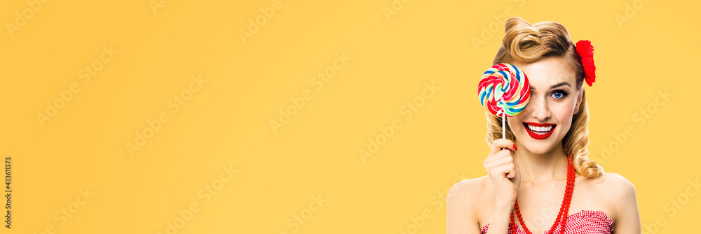 Half face portrait of excited woman with lollipop covering one eye. Pin up girl with happy smile. Retro style image. Orange yellow color background. Ophthalmology concept. Half face portrait of excited woman with lollipop covering one eye. Pin up girl with happy smile. Retro style image. Orange yellow color background. Ophthalmology concept.