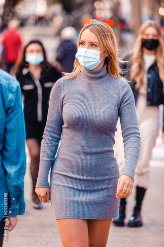 Blond woman wearing protective mask walking on the street