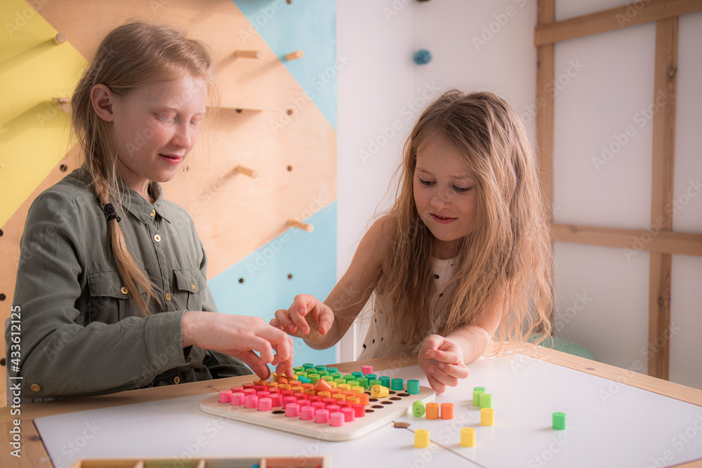 Two sisters play a board game, girls learn math and multiplication tables, children laugh together. Two sisters play a board game, girls learn math and multiplication tables, children laugh together.