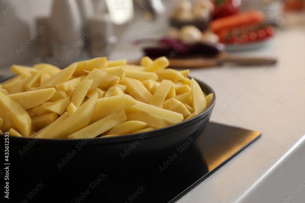 Frying pan with cut raw potatoes on cooktop, closeup. Space for text Frying pan with cut raw potatoes on cooktop, closeup. Space for text