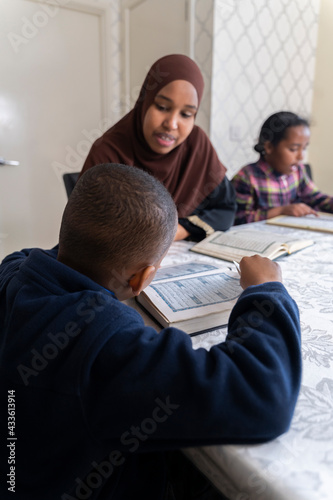 Black Muslim mother reading quran with her children