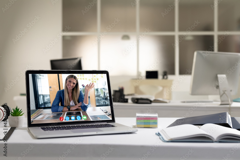 Laptop computer with a video call from businesswoman lying on desk Laptop computer with a video call from businesswoman lying on desk