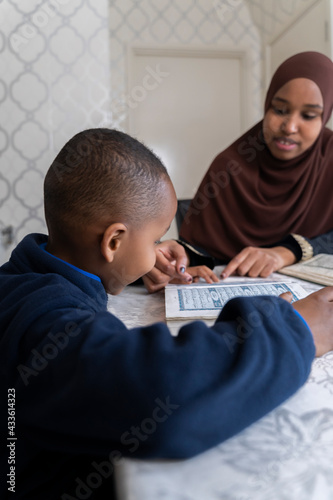Black Muslim mother reading quran with her children