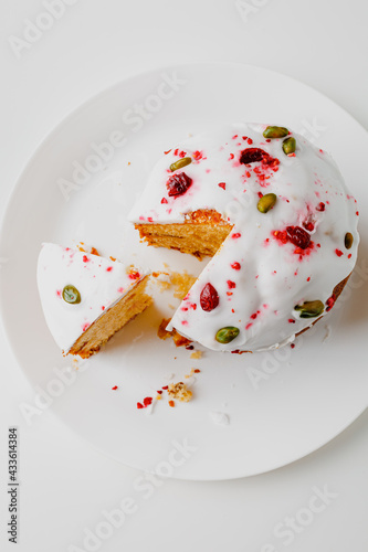 Easter muffin cake with pistachios and cranberry and easter decorations on a white plate. White background. Copy space. 