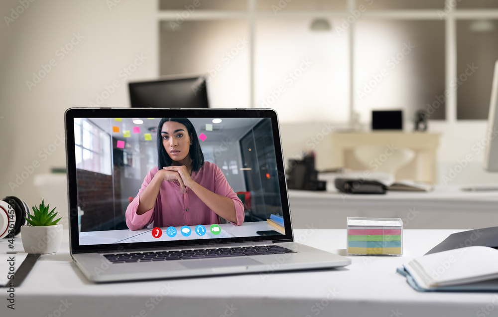 Laptop computer with a video call from businesswoman lying on desk Laptop computer with a video call from businesswoman lying on desk