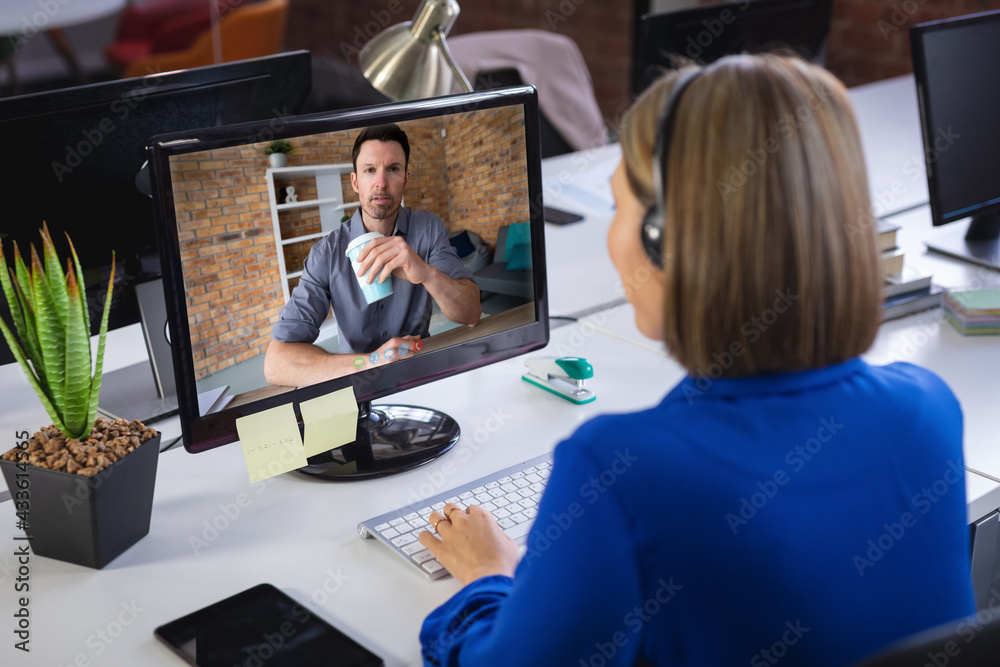 Caucasian businesswoman sitting at desk using computer having video call with male colleague