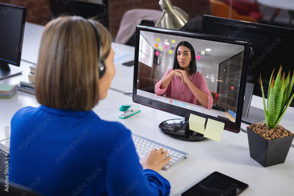 Caucasian businesswoman sitting at desk using computer having video call with female colleague Caucasian businesswoman sitting at desk using computer having video call with female colleague