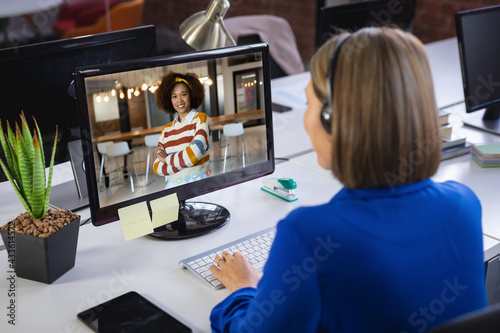 Caucasian businesswoman sitting at desk using computer having video call with female colleague