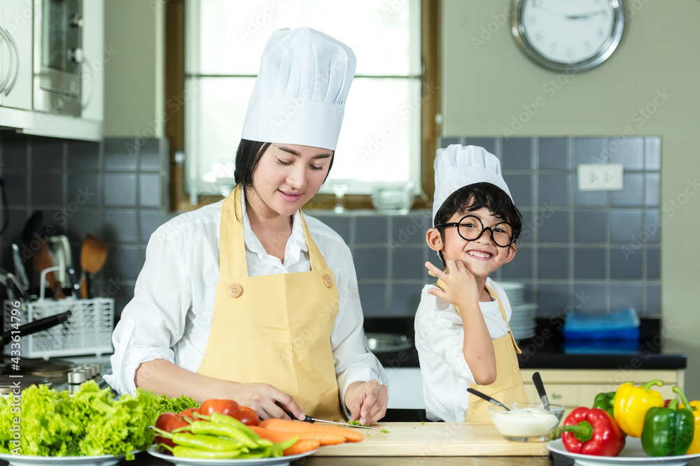 Cooking Family. Chef kid boy and mother making and leaning fresh vegetables salad for healthy eat and education. Asian son helping make food, so happy and enjoy. Family Lifestyle Concept Cooking Family. Chef kid boy and mother making and leaning fresh vegetables salad for healthy eat and education. Asian son helping make food, so happy and enjoy. Family Lifestyle Concept