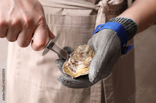 Foto Man opening fresh oyster with knife, closeup