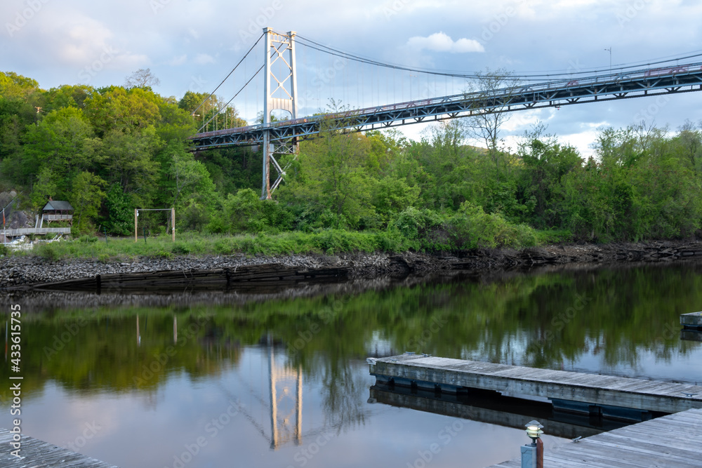 Kingston, NY - USA- May 12, 2021: a landscape view of the Wurts Street Bridge or the The Kingston–Port Ewen Suspension Bridge, is a steel suspension bridge spanning Rondout Creek.