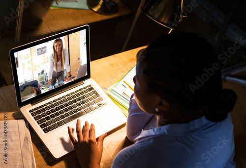 Caucasian woman sitting at desk having video call with coworker