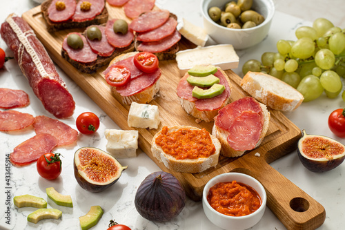 Assortment of sausages and cheese, salami, grapes, baguette slices, olives, on white background. Close up