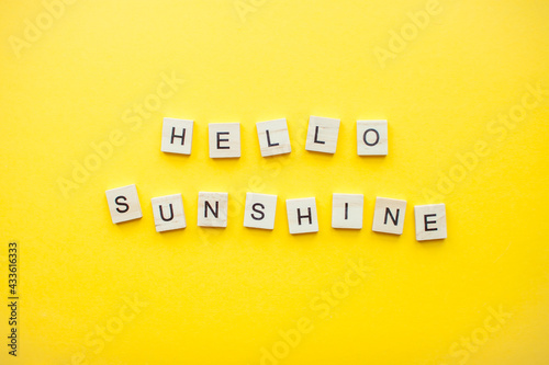 The inscription from wooden cubes hello sunshine on a bright yellow background. High quality photo