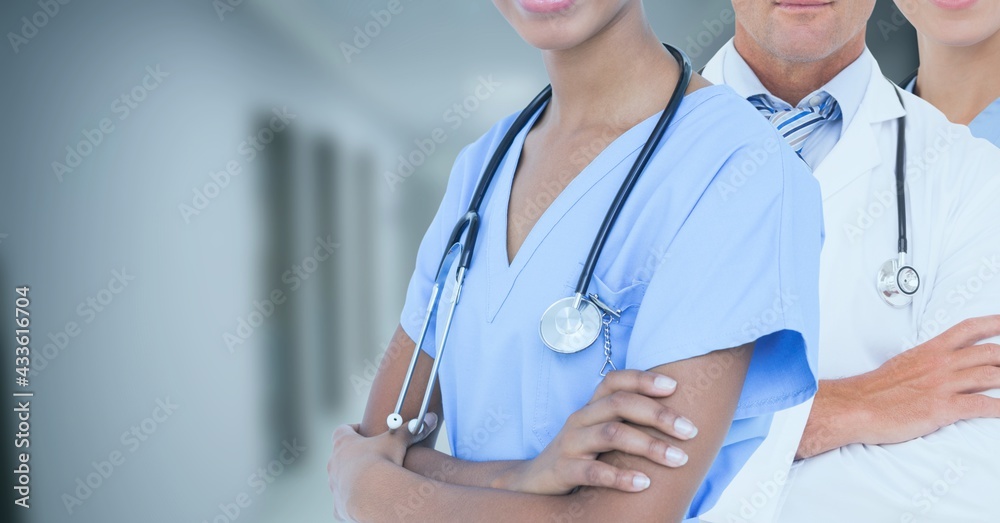 Mid section of team of medical professionals and health workers against hospital in background Mid section of team of medical professionals and health workers against hospital in background
