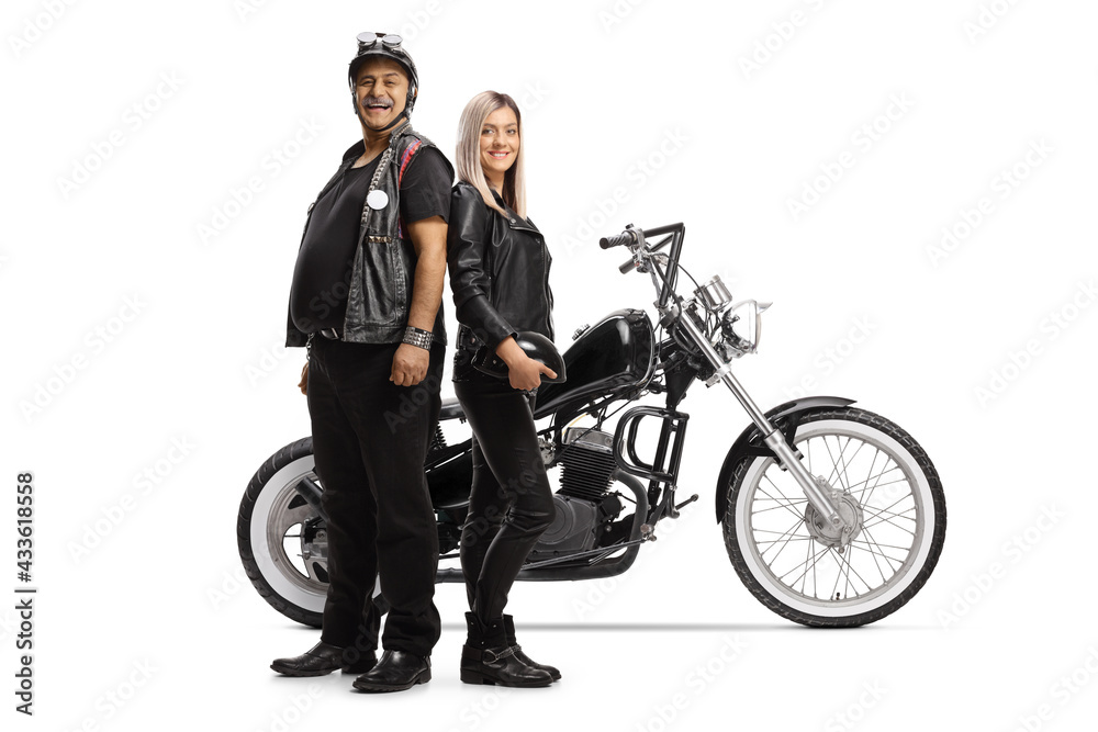 Mature biker and a young woman in leather clothes posing in front of a chopper Mature biker and a young woman in leather clothes posing in front of a chopper