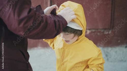 Mom puts on a little girl hood in a strong wind. The hurricane overtook the family suddenly and the child is confused. The concept of the elements and the storm