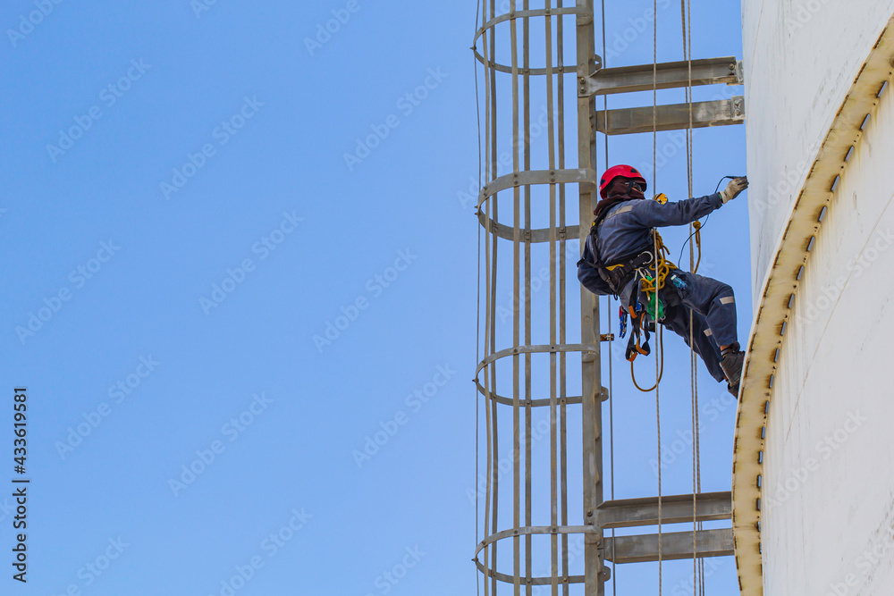 Fototapeta premium Male worker rope access height safety inspection of thickness storage oil and gas tank
