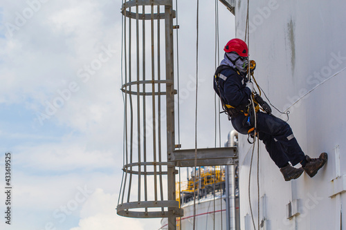 Male worker rope access height safety inspection of thickness storage oil and gas tank