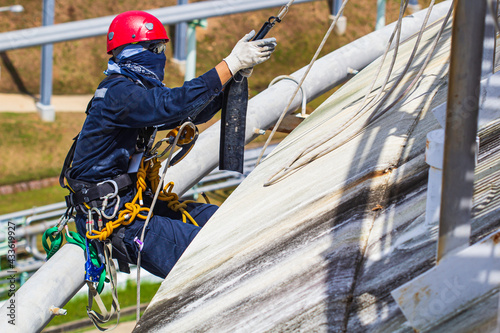 Male worker rope access height safety inspection of thickness storage oil and gas tank