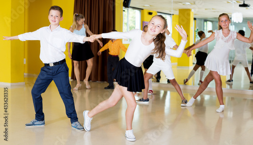 Glad boys and girls enjoying active dance in studio