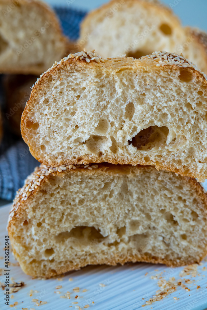 Fresh challah bread rolls hot from the oven cut into half. Crumb shot of gluten free bread buns or mini loaves with sesame seeds and golden color. Fluffy homemade bread wrapped in a towel ready to eat