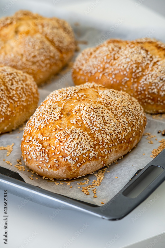 Fresh challah bread rolls hot from the oven on baking tray. Gluten free bread buns or mini loaves with sesame seeds and golden color ready to eat. Fluffy shaped bread for sandwiches, lunch and dinner.