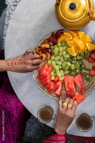Women with henna on fingers eating fruit from fruit platter