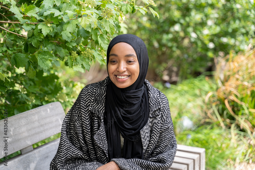 Black Muslim woman on a park bench Stock Photo | Adobe Stock