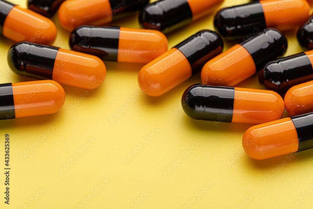 Medicinal capsules on a yellow background, close-up. Health concept, pharmaceutical medicine.