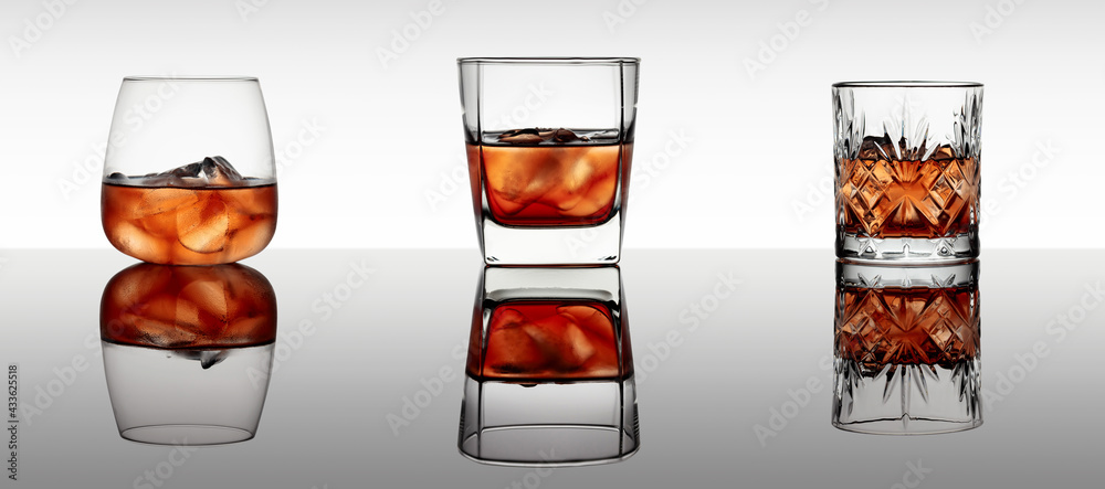 Three various glasses of whiskey with ice on a black reflective background. - obrazy, fototapety, plakaty 