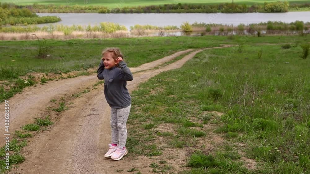 Cheerful moments of childhood in the village. Walk of a girl 4 years old in nature. The child runs on the grass. Cheerful moments of childhood in the village. Walk of a girl 4 years old in nature. The child runs on the grass.