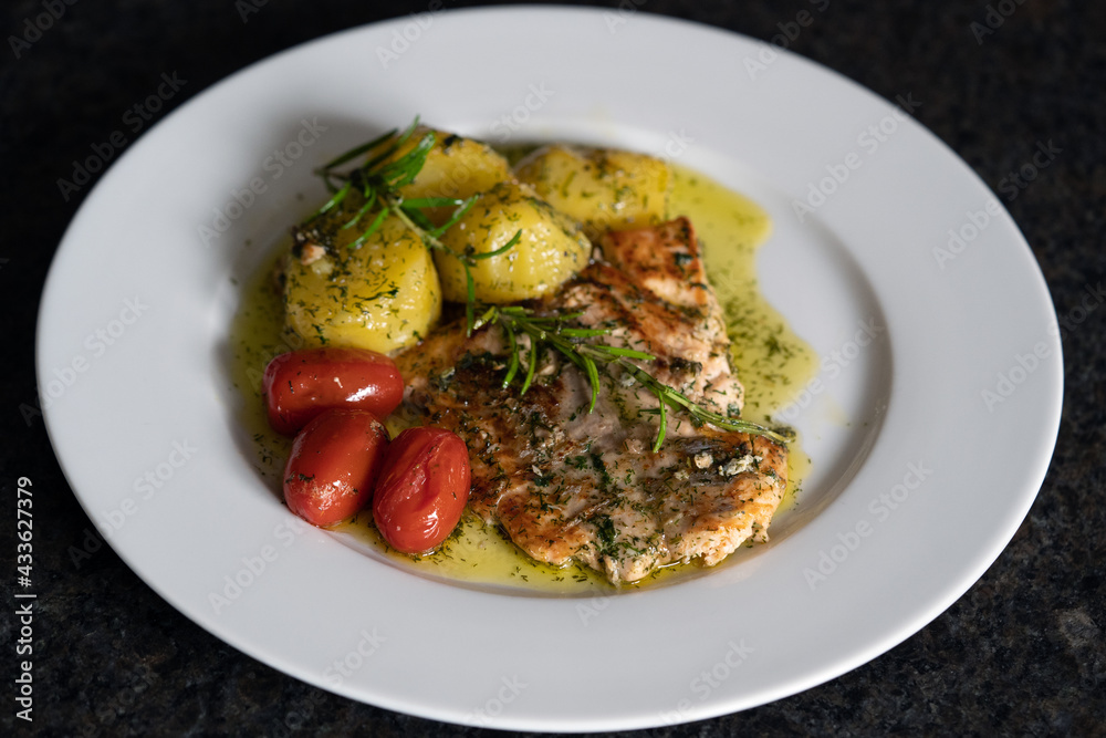 fresh cooking at home and ready to eat - grilled salmon fillet with rosemary, cherry tomatoes and fried potatoes in butter and herbs