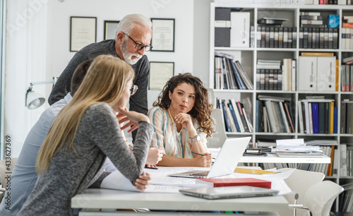 Senior designer manager explaining to his female coworkers how to solve problem.Working day in design studio. 