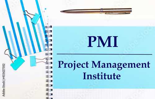 On a light background - light blue diagrams, paper clips and a sheet of paper with the text PMI Project Management Institute. View from above. Business concept photo