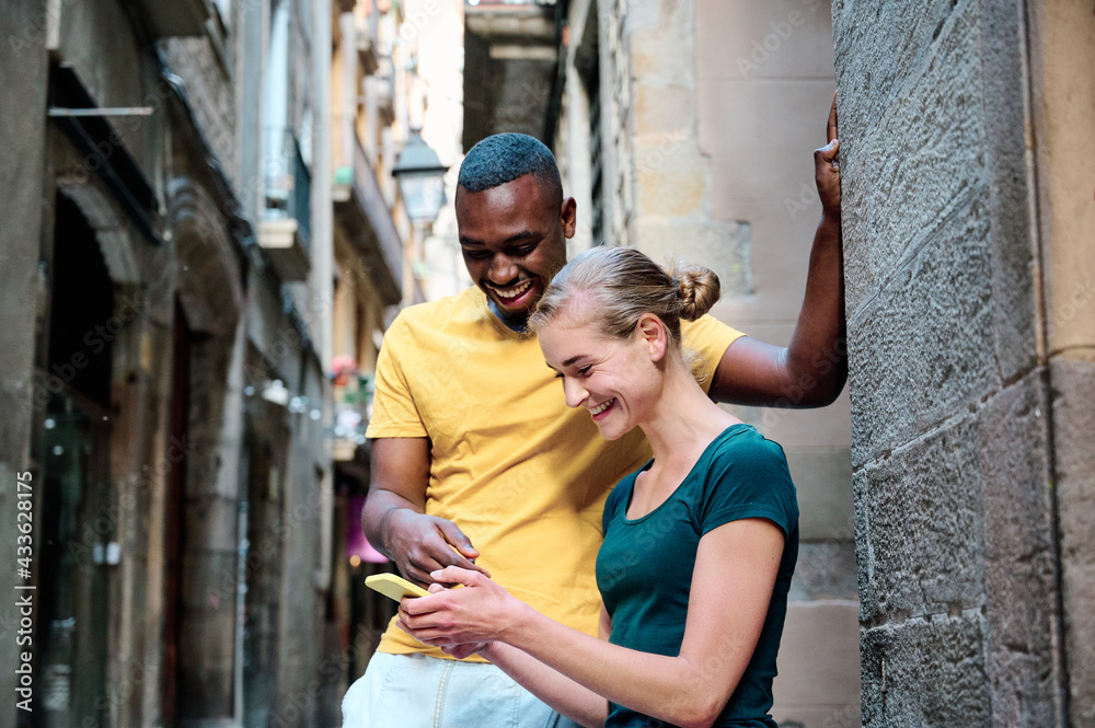 young interracial couple using msartphone and smiling at El Borne Barcelona