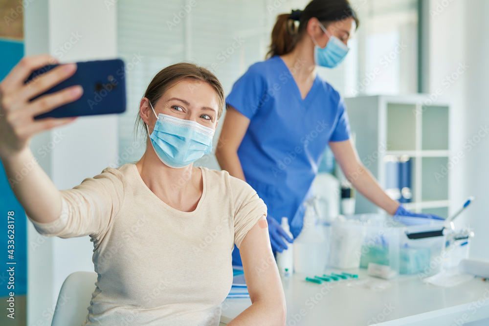 Woman taking a selfie while getting a COVID-19 vaccine Woman taking a selfie while getting a COVID-19 vaccine