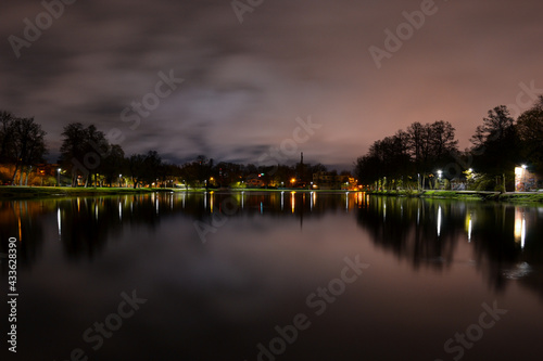 Night landscape. A lake with wonderfully calm water which reflects the lanterns of the park.