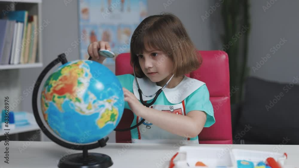 Little girl is dressed in medical clothes with a stethoscope in her hands examines and plays a game of healing the planet Earth. World planet earth eco friendly. Sick earth planet Covid-19 symptoms. Little girl is dressed in medical clothes with a stethoscope in her hands examines and plays a game of healing the planet Earth. World planet earth eco friendly. Sick earth planet Covid-19 symptoms.